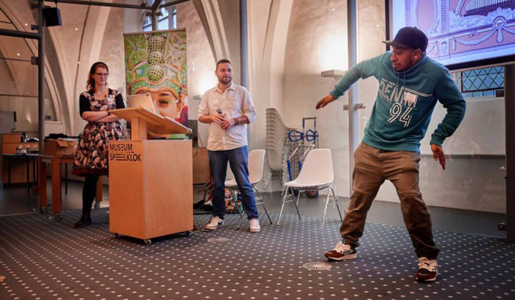 Danser voert een energieke beweging uit tijdens een presentatie in Museum Speelklok, symbool voor kunst, educatie en expressie